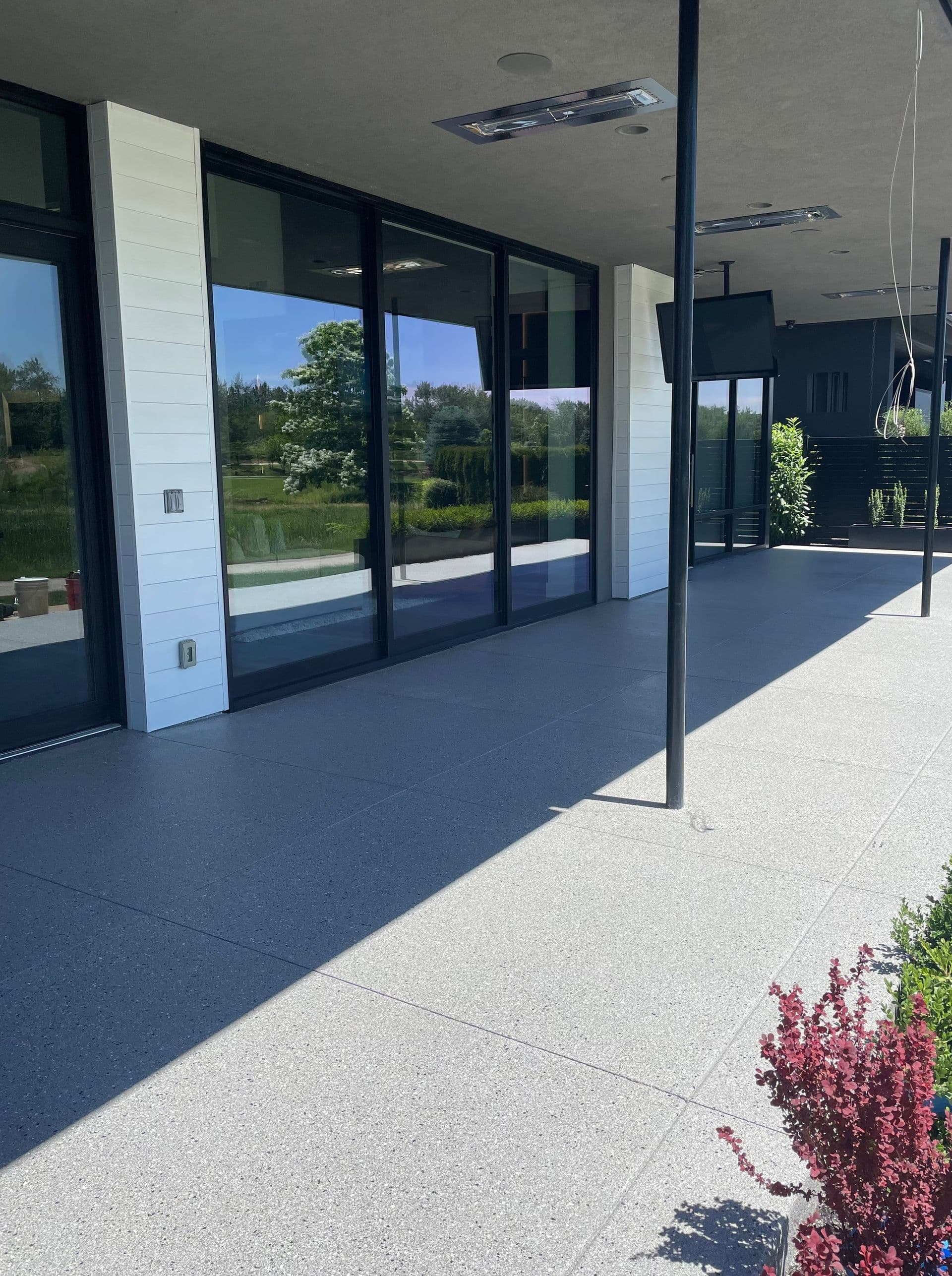 Gray patio coating in front of a building with floor-to-ceiling windows.