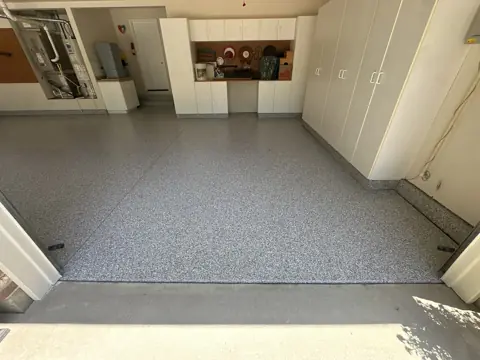 Kent Q.'s finished garage floor in a gray flake coating, with white storage cabinets along the wall.